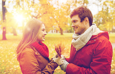 Image showing happy couple with maple leaves in autumn park