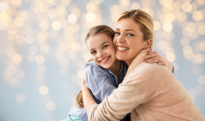 Image showing happy girl with mother hugging over lights