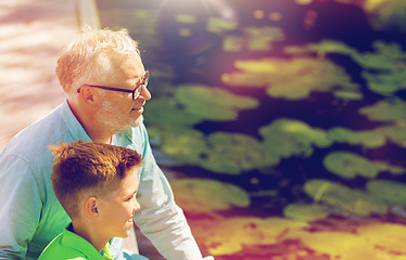 Image showing grandfather and grandson sitting on river berth