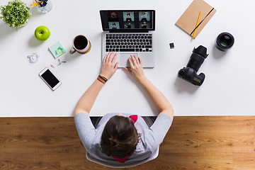 Image showing woman with camera working on laptop at table