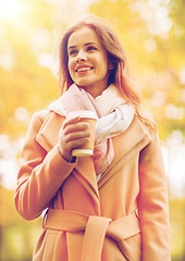 Image showing happy young woman drinking coffee in autumn park