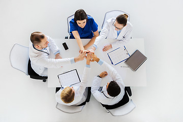 Image showing group of doctors making high five at table