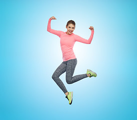 Image showing happy smiling sporty young woman jumping in air