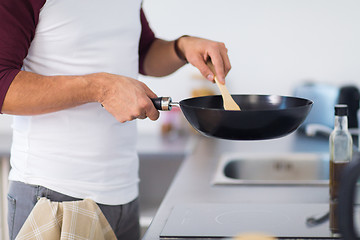 Image showing man with frying pan cooking food at home kitchen