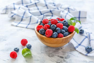 Image showing Fresh raspberries and blueberries in wooden bowl.