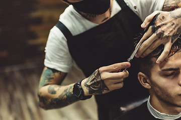 Image showing Crop barber doing haircut for client