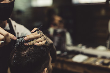 Image showing Crop barber doing haircut for client