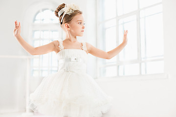 Image showing Little ballerina girl in a tutu. Adorable child dancing classical ballet in a white studio.