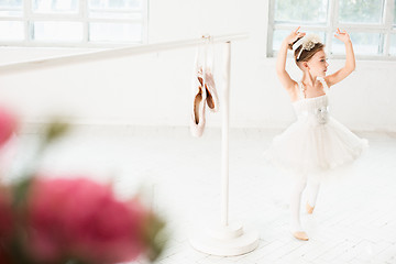 Image showing Little ballerina girl in a tutu. Adorable child dancing classical ballet in a white studio.