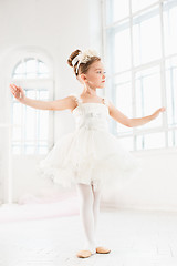 Image showing Little ballerina girl in a tutu. Adorable child dancing classical ballet in a white studio.
