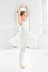 Image showing Little ballerina girl in a tutu. Adorable child dancing classical ballet in a white studio.