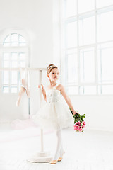 Image showing Little ballerina girl in a tutu. Adorable child dancing classical ballet in a white studio.