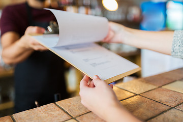 Image showing bartender showing menu to customer at bar