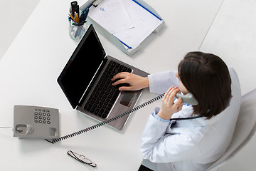 Image showing doctor with laptop calling on phone at clinic