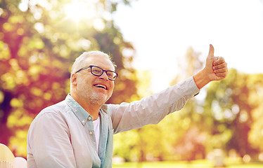 Image showing happy senior man showing thumbs up at summer park