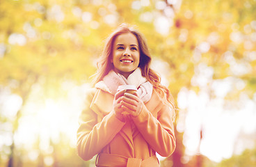 Image showing happy young woman drinking coffee in autumn park