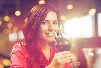 Image showing smiling woman drinking red wine at restaurant