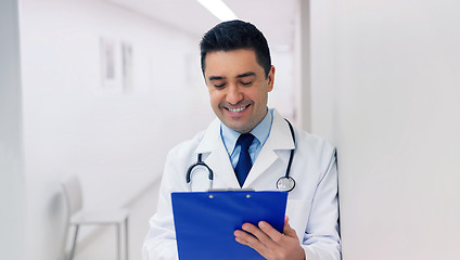 Image showing happy doctor writing to clipboard at hospital