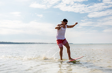 Image showing young man riding on skimboard on summer beach