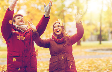 Image showing happy young couple throwing autumn leaves in park