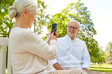 Image showing old woman photographing man by smartphone in park