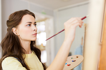 Image showing student girl with easel painting at art school