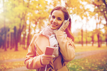 Image showing woman with smartphone and earphones in autumn park