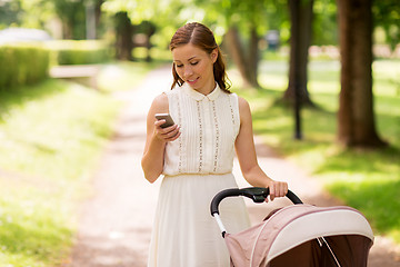 Image showing happy mother with smartphone and stroller at park