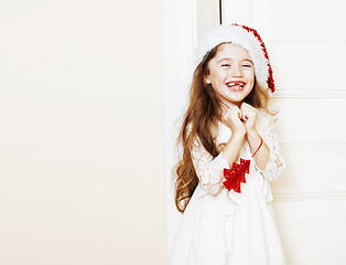 Image showing little cute girl in santas red hat waiting for Christmas gifts. 