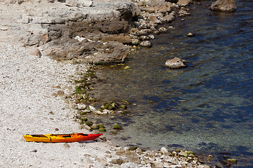 Image showing Orange kayak on pebbly beach of sea coast