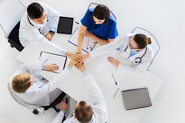 Image showing group of doctors holding hands together at table