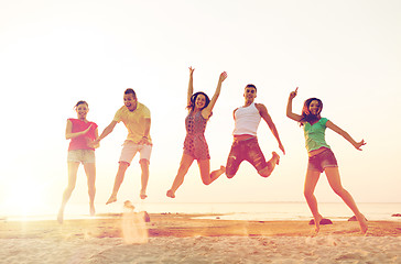 Image showing smiling friends dancing and jumping on beach