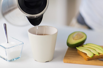 Image showing kettle pouring hot water to tea cup at home