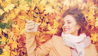 Image showing woman on autumn leaves taking selfie by smartphone