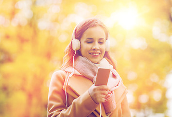 Image showing woman with smartphone and earphones in autumn park