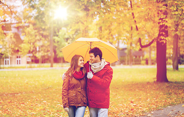 Image showing smiling couple with umbrella in autumn park