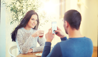 Image showing man taking picture of woman by smartphone at cafe