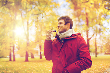 Image showing man recording voice on smartphone at autumn park