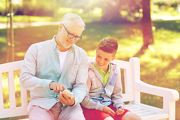 Image showing old man and boy with smartphones at summer park
