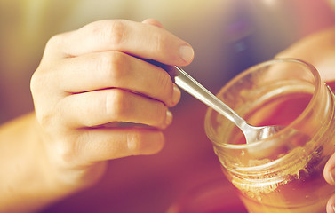 Image showing close up of woman hands with honey and spoon