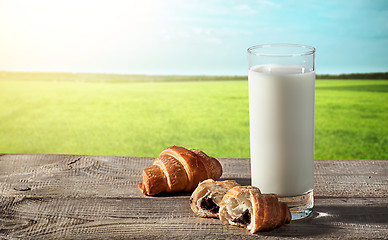 Image showing Glass of milk on rustic table with croissants