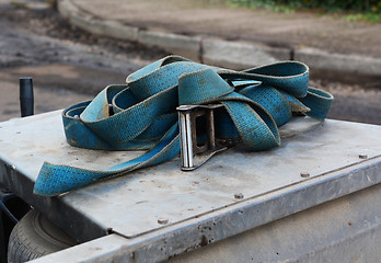 Image showing Blue strap with a metal buckle on a trailer