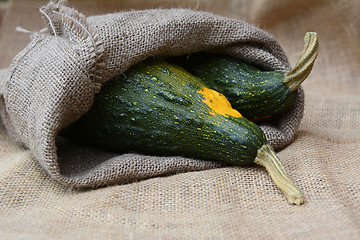 Image showing Large green and yellow ornamental gourds in burlap sack