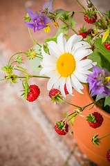 Image showing Ripe strawberries and a bouquet of forest flowers in a clay mug