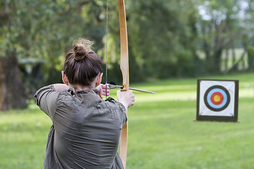 Image showing Woman archer to use a bow and arrow and shoot at a target
