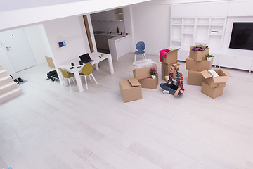 Image showing woman with many cardboard boxes sitting on floor
