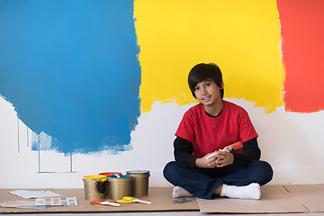 Image showing young boy painter resting after painting the wall