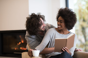 Image showing multiethnic couple hugging in front of fireplace