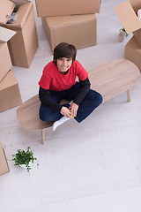 Image showing boy sitting on the table with cardboard boxes around him top vie