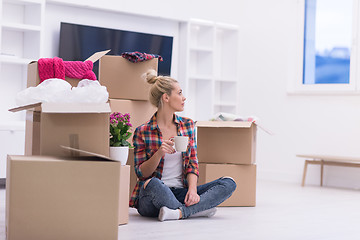 Image showing woman with many cardboard boxes sitting on floor